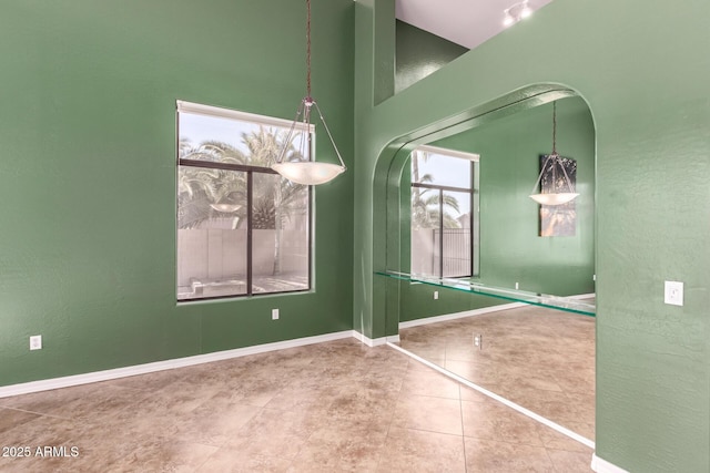 tiled empty room featuring a textured wall and baseboards