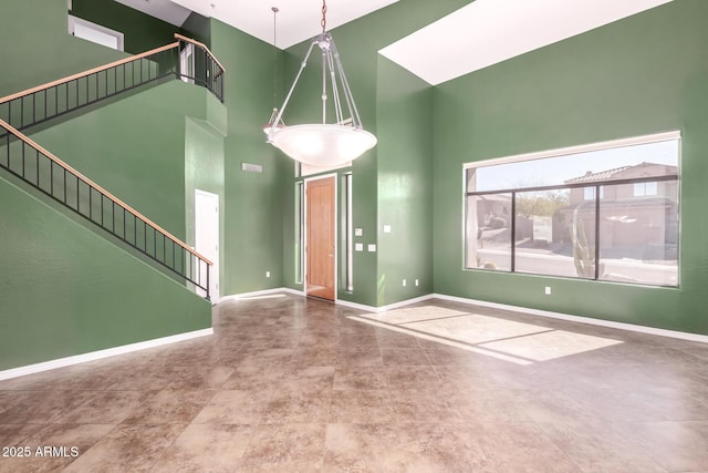 interior space featuring stairs, a towering ceiling, and baseboards