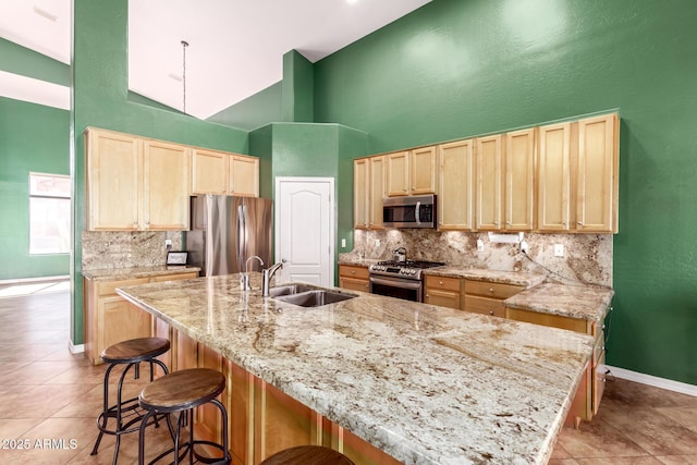 kitchen featuring light brown cabinetry, appliances with stainless steel finishes, backsplash, and a sink