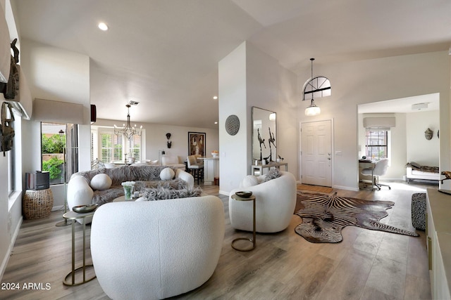 living room featuring a chandelier, light hardwood / wood-style floors, and high vaulted ceiling