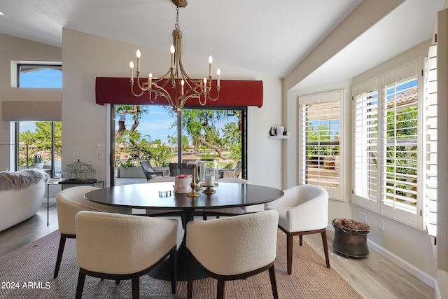 dining area featuring hardwood / wood-style flooring, an inviting chandelier, and vaulted ceiling