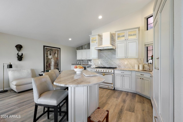 kitchen with stainless steel range, wood-type flooring, lofted ceiling, and custom exhaust hood