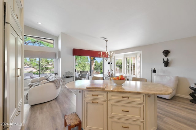 kitchen featuring light hardwood / wood-style flooring, cream cabinets, vaulted ceiling, decorative light fixtures, and a kitchen island