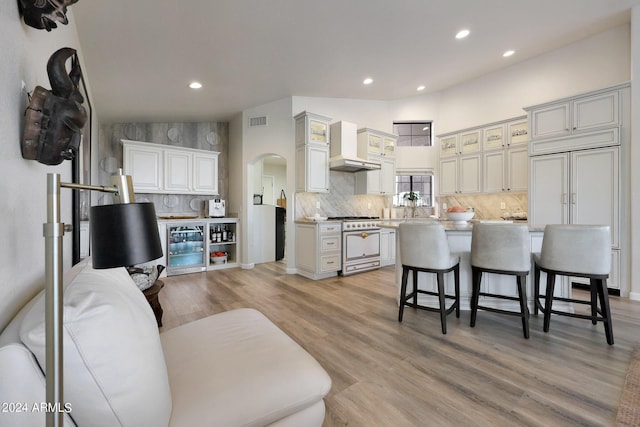 kitchen with a center island, light hardwood / wood-style flooring, vaulted ceiling, wall chimney exhaust hood, and premium appliances