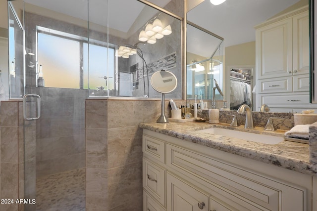 bathroom with a shower with door, vanity, and vaulted ceiling