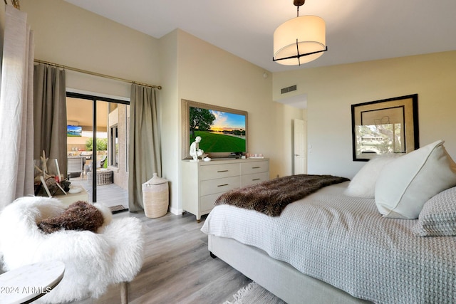 bedroom featuring access to outside, light hardwood / wood-style flooring, and lofted ceiling