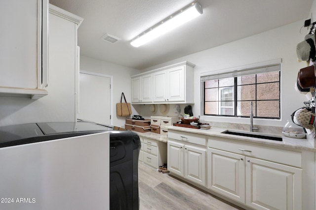 kitchen with white cabinets, light hardwood / wood-style floors, and sink