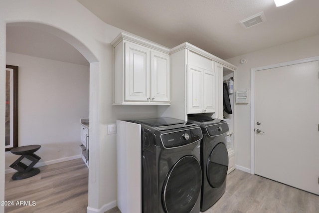 washroom featuring cabinets, independent washer and dryer, and light hardwood / wood-style flooring