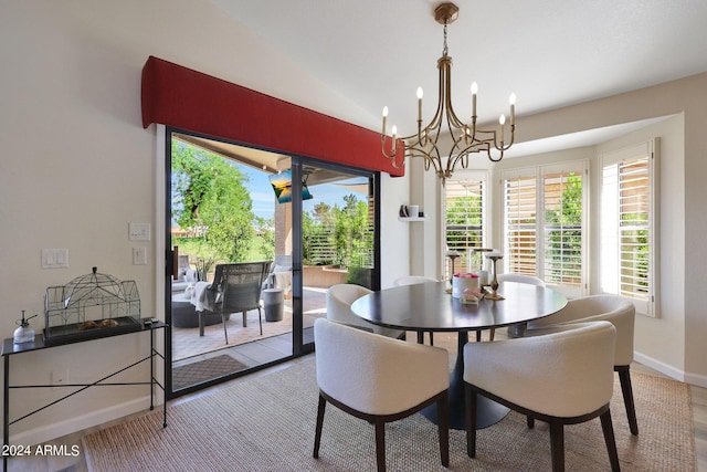 dining area featuring hardwood / wood-style flooring, an inviting chandelier, and vaulted ceiling