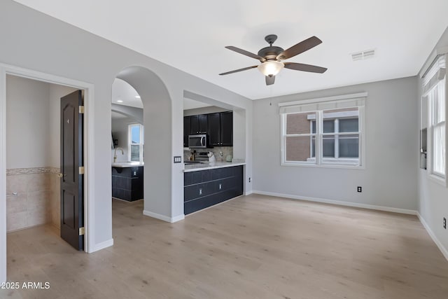 3687 E Leslie Dr, Gilbert, AZ 85296 - unfurnished living room with light wood-style flooring, ceiling fan, a sink, tile walls, and arched walkways