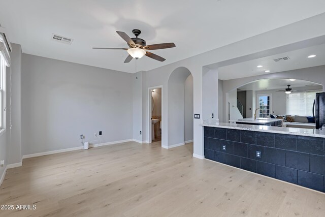 3687 E Leslie Dr, Gilbert, AZ 85296 - unfurnished bedroom featuring arched walkways, light wood-style floors, black refrigerator, and baseboards