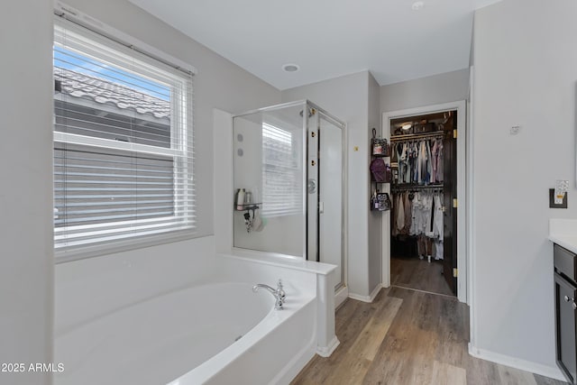3687 E Leslie Dr, Gilbert, AZ 85296 - bathroom with vanity, a shower stall, a bath, wood finished floors, and a spacious closet