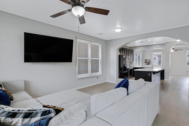 3687 E Leslie Dr, Gilbert, AZ 85296 - living room featuring a ceiling fan, arched walkways, light wood finished floors, and baseboards