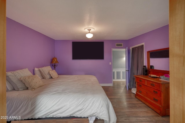 bedroom featuring wood finished floors, visible vents, and baseboards