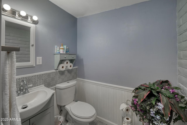 bathroom featuring toilet, vanity, and wainscoting