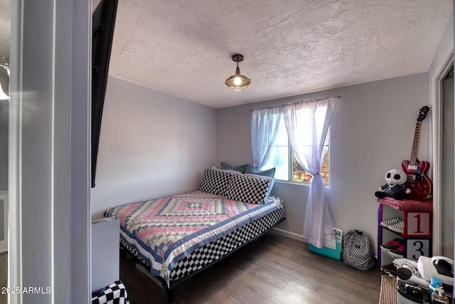 bedroom featuring a textured ceiling, wood finished floors, and baseboards