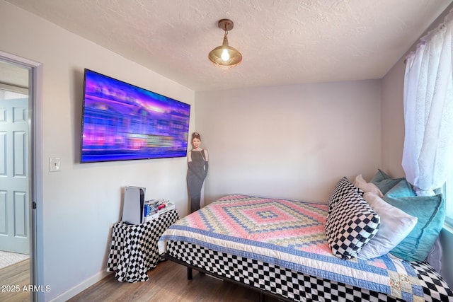 bedroom featuring a textured ceiling, baseboards, and wood finished floors