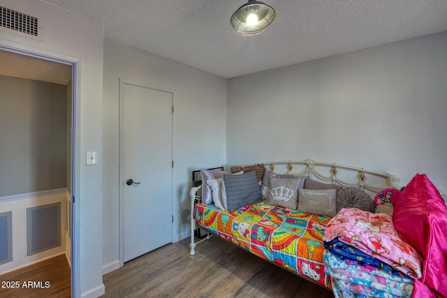 bedroom featuring visible vents, a textured ceiling, and wood finished floors