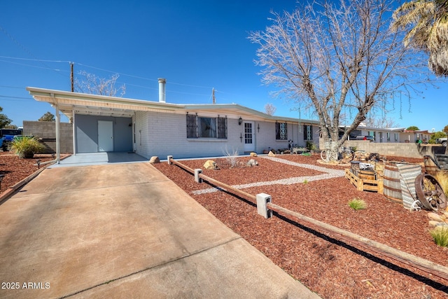 ranch-style house featuring concrete driveway, brick siding, and an attached carport