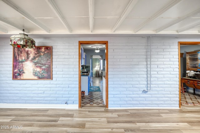 spare room with brick wall and wood finished floors