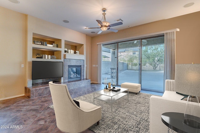 living room featuring a tile fireplace, ceiling fan, and built in features