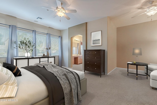 bedroom with light colored carpet, ensuite bath, and ceiling fan