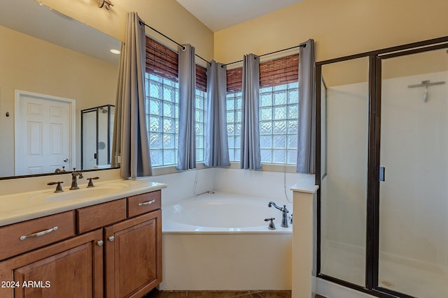 bathroom with a healthy amount of sunlight, vanity, and independent shower and bath