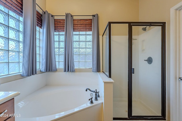 bathroom with separate shower and tub, vanity, and a healthy amount of sunlight