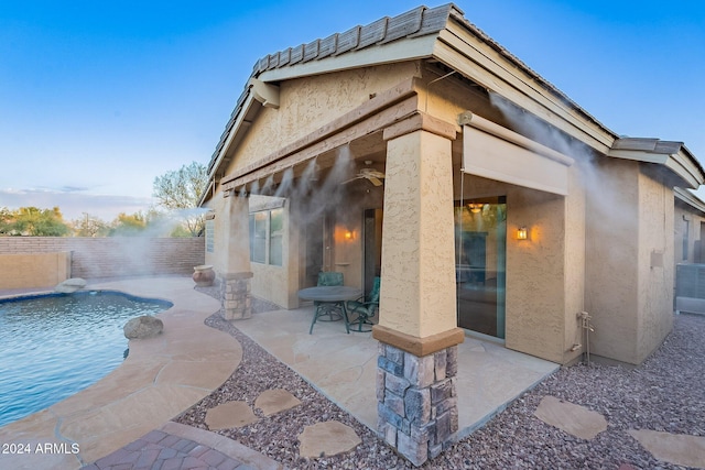 rear view of property featuring a patio and a fenced in pool