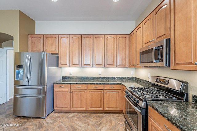 kitchen featuring appliances with stainless steel finishes and dark stone counters