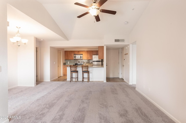 living room with visible vents, high vaulted ceiling, light carpet, and ceiling fan with notable chandelier