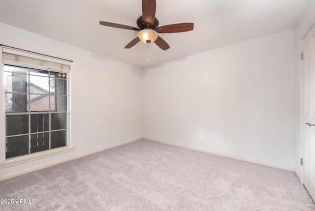 carpeted empty room with a ceiling fan and baseboards