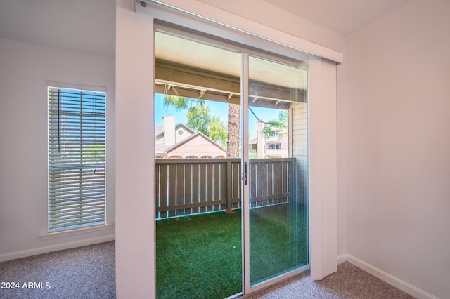 doorway featuring baseboards, a healthy amount of sunlight, and carpet