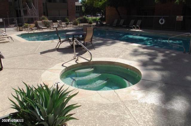 community pool featuring a patio area, a hot tub, and fence