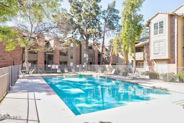 community pool with a residential view, a patio area, and fence