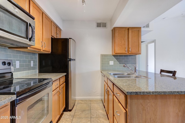 kitchen with backsplash, visible vents, a sink, a peninsula, and appliances with stainless steel finishes