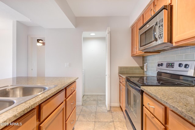 kitchen with brown cabinetry, backsplash, baseboards, and stainless steel appliances