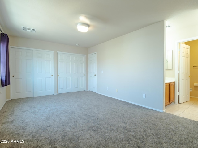 2826 E Tracy Ln Unit 3, Phoenix, AZ 85032 - unfurnished bedroom featuring two closets, light colored carpet, baseboards, and connected bathroom