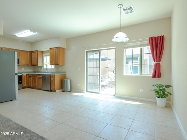 2826 E Tracy Ln Unit 3, Phoenix, AZ 85032 - kitchen featuring appliances with stainless steel finishes, light countertops, light tile patterned flooring, brown cabinetry, and hanging light fixtures