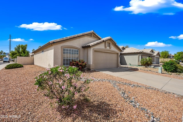 view of front facade featuring a garage, stucco siding, driveway, and fence