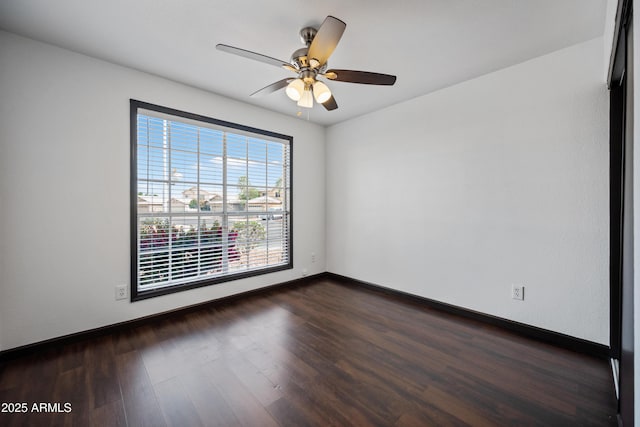 empty room featuring baseboards, dark wood-style flooring, and ceiling fan