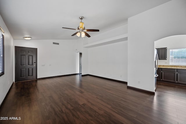 unfurnished living room with ceiling fan, dark wood-type flooring, and baseboards