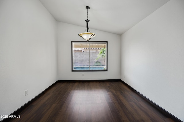 spare room featuring lofted ceiling, dark wood-style flooring, and baseboards