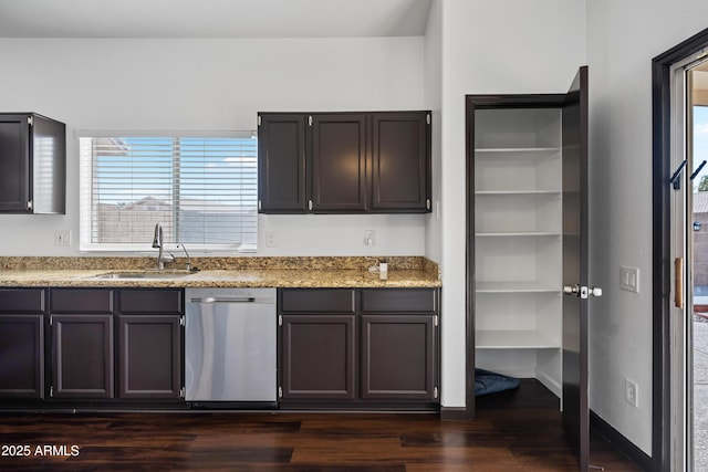 kitchen with stainless steel dishwasher, a sink, dark wood-type flooring, and light stone countertops