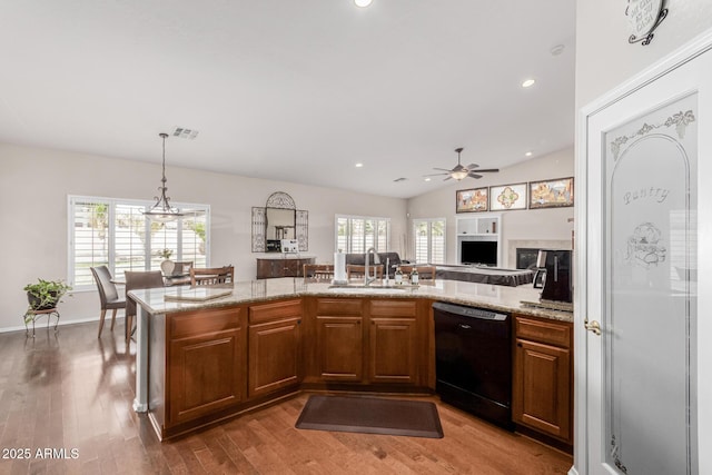 kitchen with light stone counters, wood finished floors, a sink, brown cabinets, and dishwasher