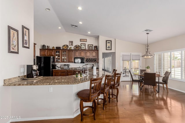 kitchen with lofted ceiling, a sink, wood finished floors, visible vents, and black appliances