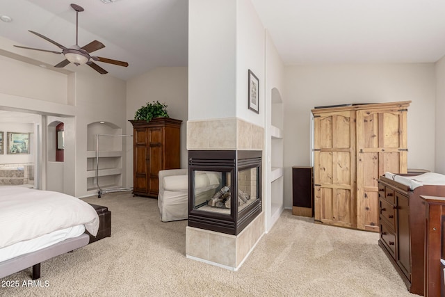 bedroom featuring arched walkways, high vaulted ceiling, a tiled fireplace, and light colored carpet