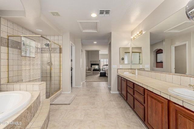 ensuite bathroom with a garden tub, a sink, visible vents, and a shower stall