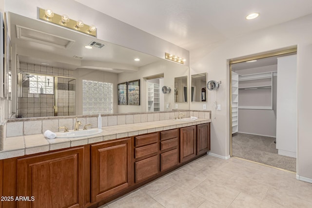 bathroom with a stall shower, a sink, and double vanity