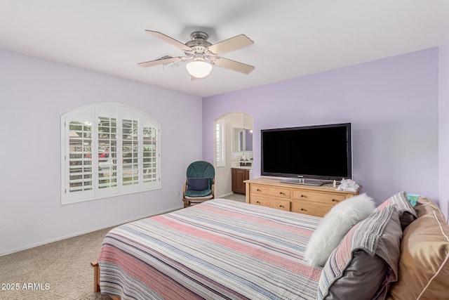 bedroom with light carpet, arched walkways, and a ceiling fan